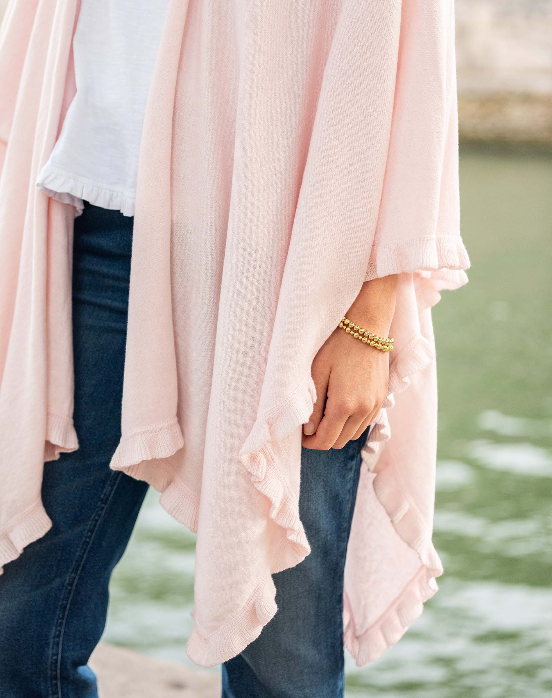 Person wearing a light pink cardigan over a white shirt with a blurred natural background