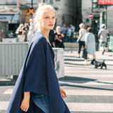 Woman in a blue coat walking on a city street with blurred background