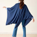 Person wearing a blue poncho and jeans against a white background