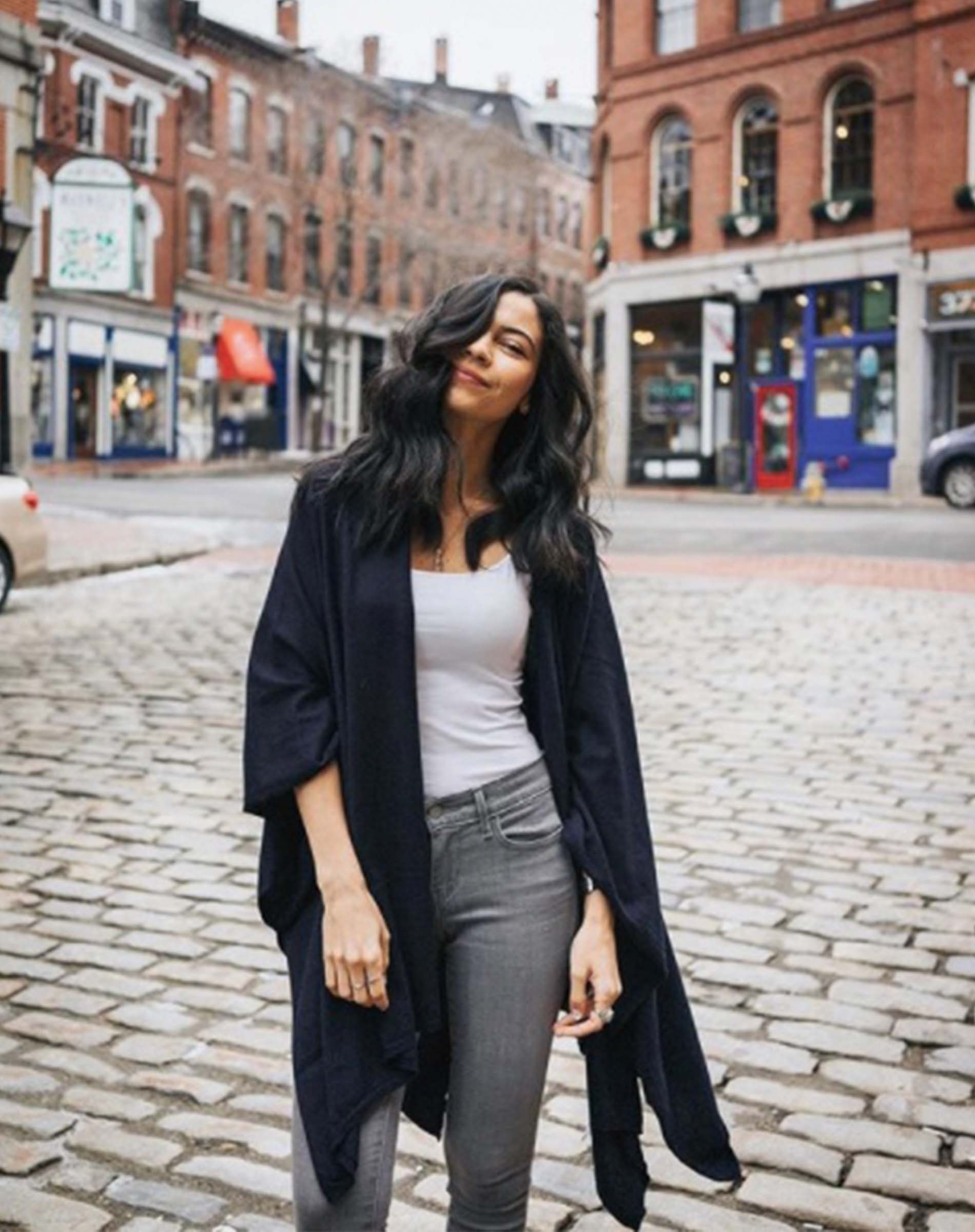 Woman standing on a cobblestone street in an urban setting
