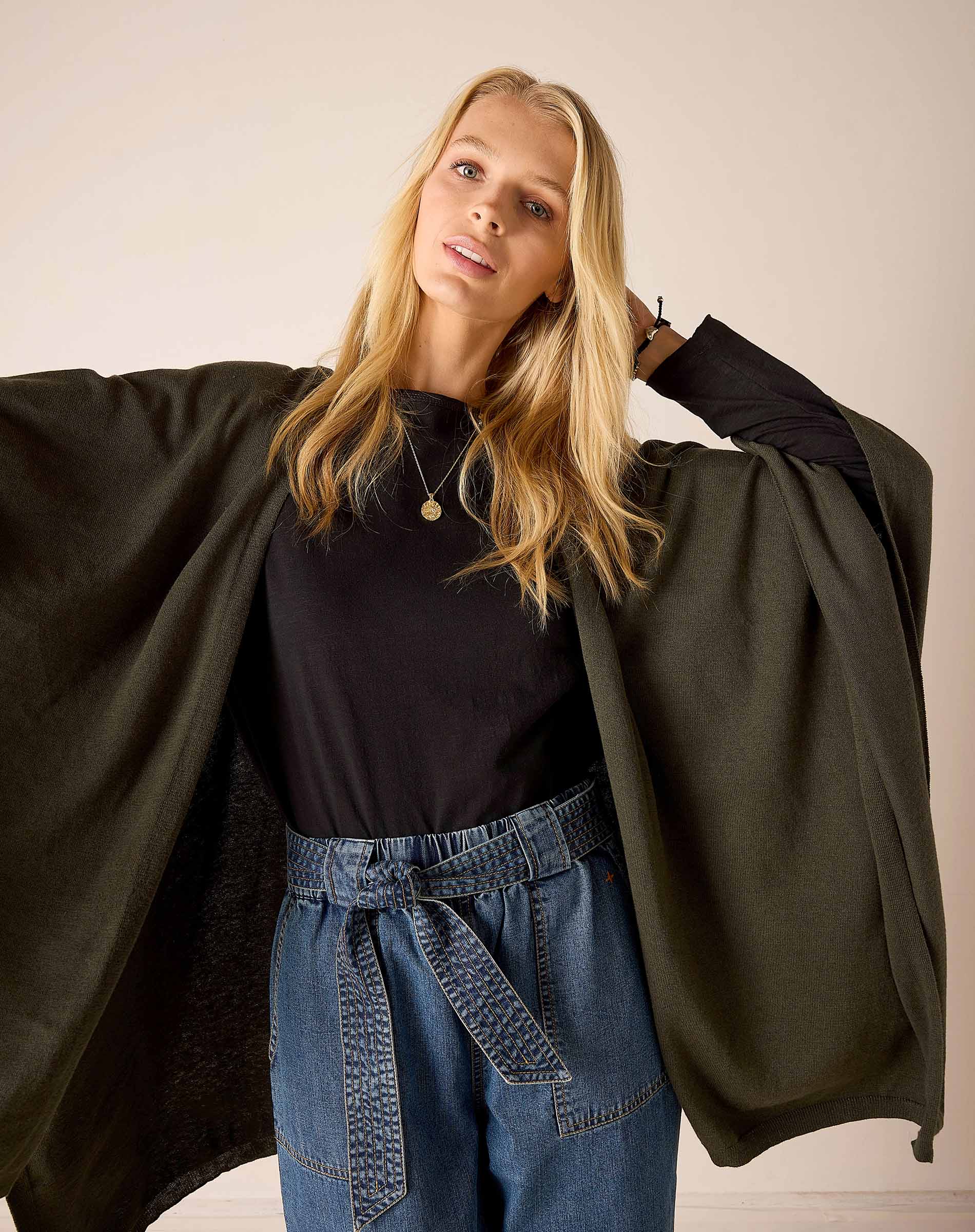 Olive green oversized knit wrap with a loose fit and draped sleeves.