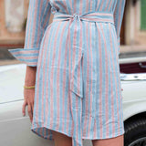 Person wearing a light blue and red striped dress with a blurred background
