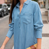 Woman wearing a blue denim dress on a city street.