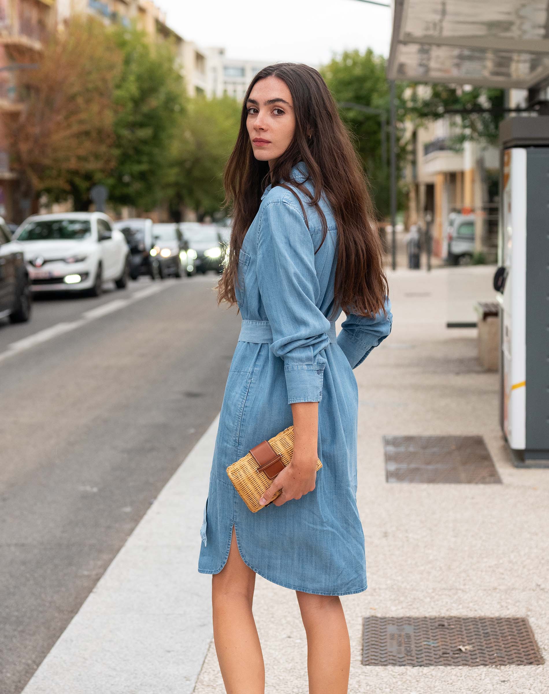 Woman in a blue dress standing on a city street