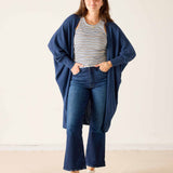 Woman wearing a blue cardigan, striped shirt, and jeans on a white background