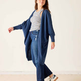 Woman wearing a blue cardigan, striped shirt, and jeans on a white background