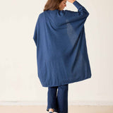Woman wearing a blue poncho and pants against a white background