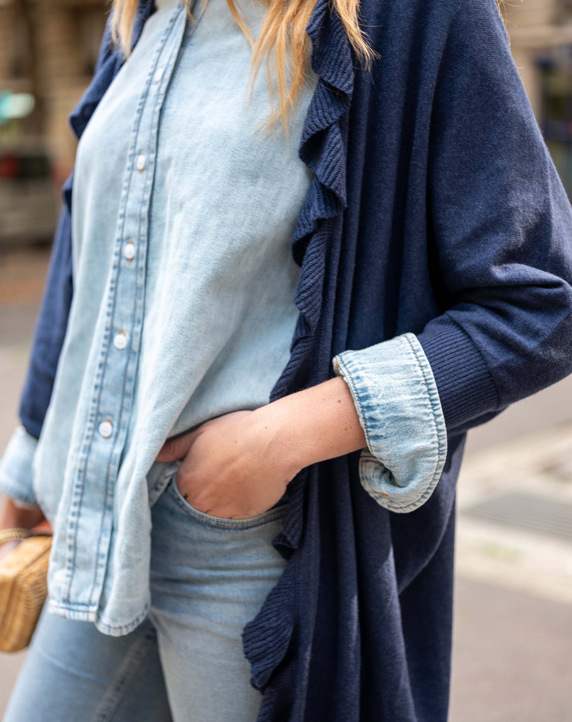Person wearing a navy cardigan over a light blue shirt and jeans.