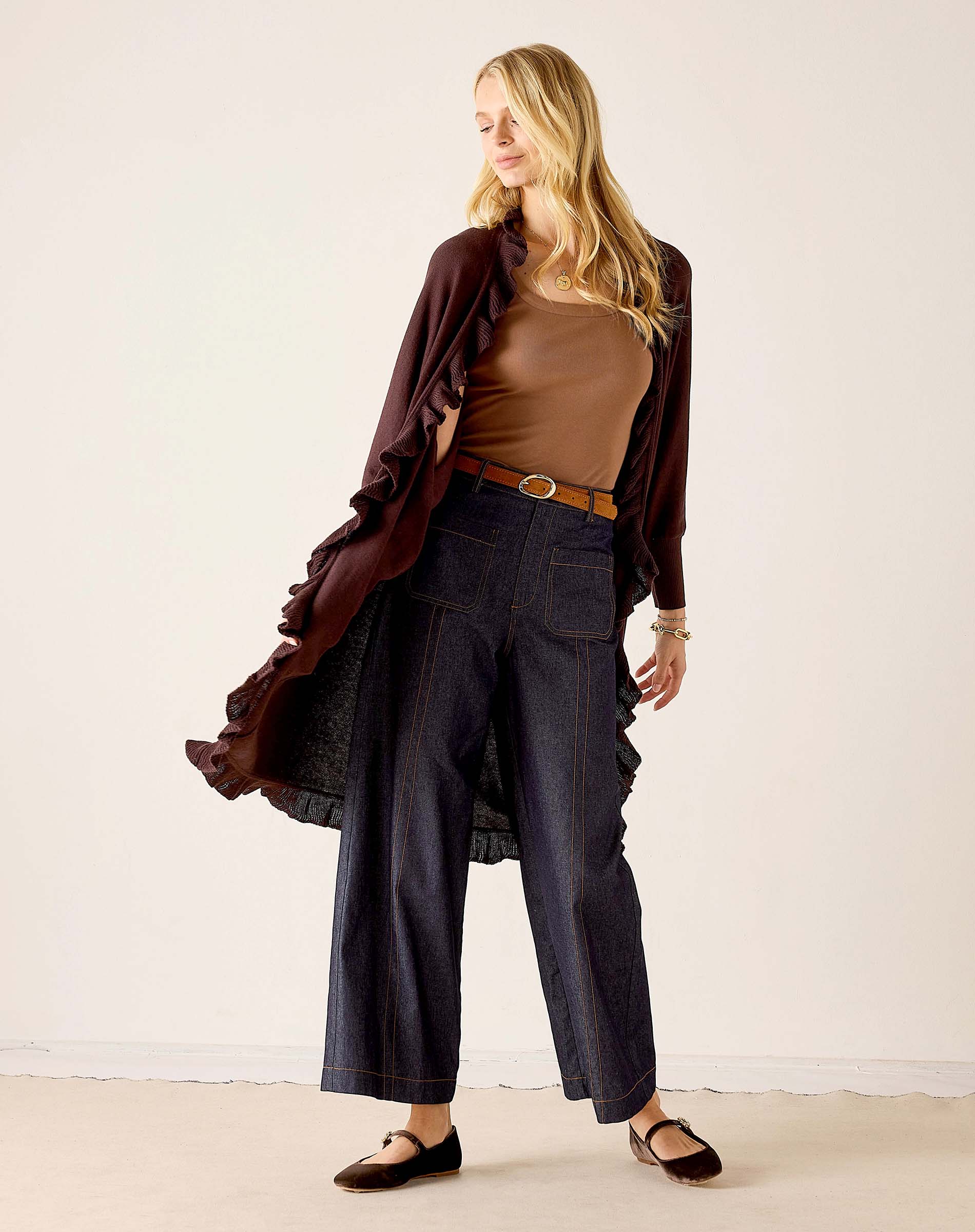 MERSEA women's travel-friendly women's travel-friendly chocolate ruffled kimono wrap worn over a brown knit top and high-waisted wide-leg jeans.