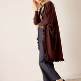 Chocolate ruffled kimono wrap worn over a top and denim pants with wide legs.