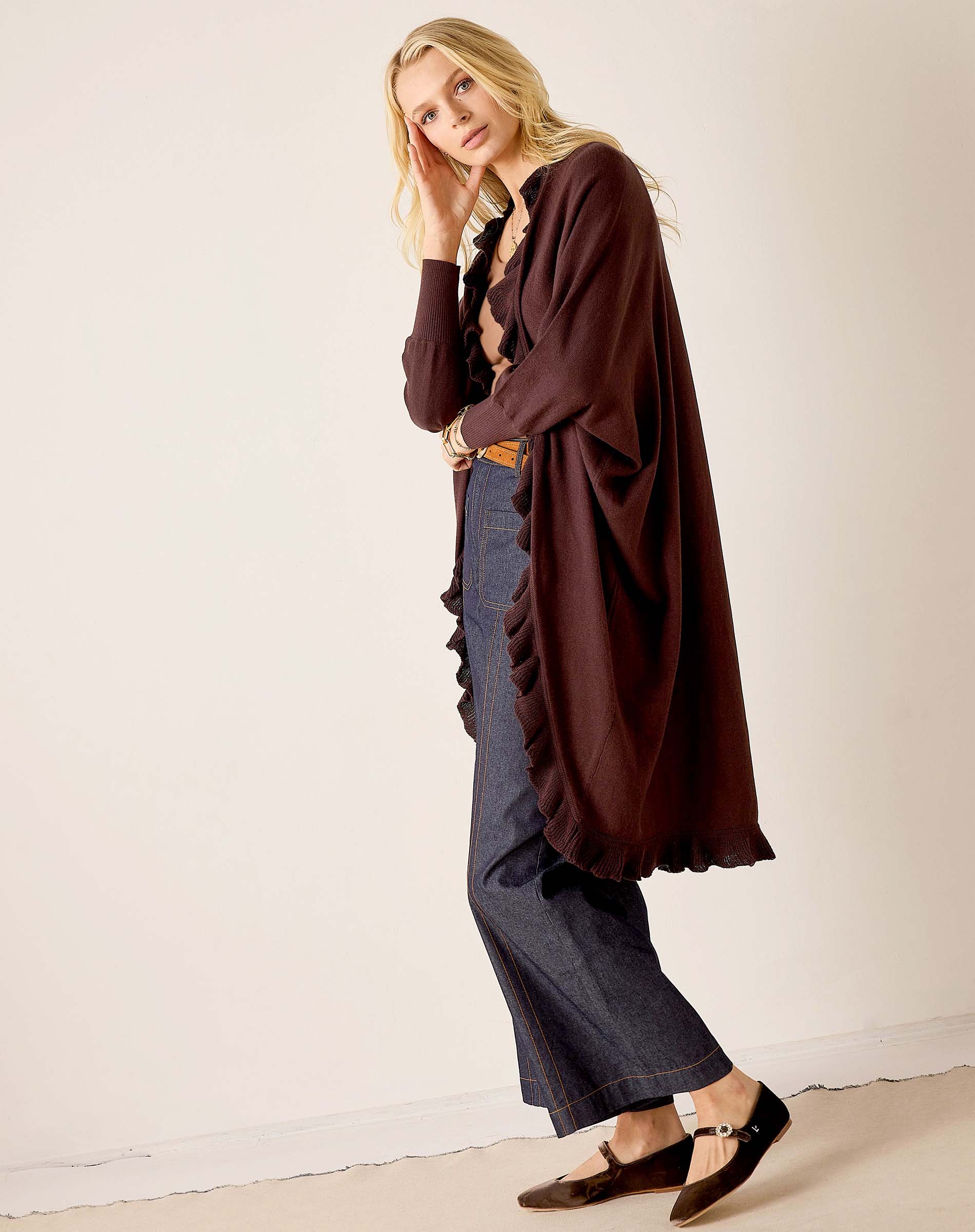 Chocolate ruffled kimono wrap worn over a top and denim pants with wide legs.