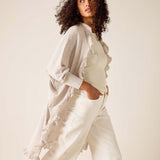 Woman wearing a light-colored outfit with a neutral background