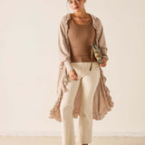 Woman wearing a beige outfit with a long duster against a white background