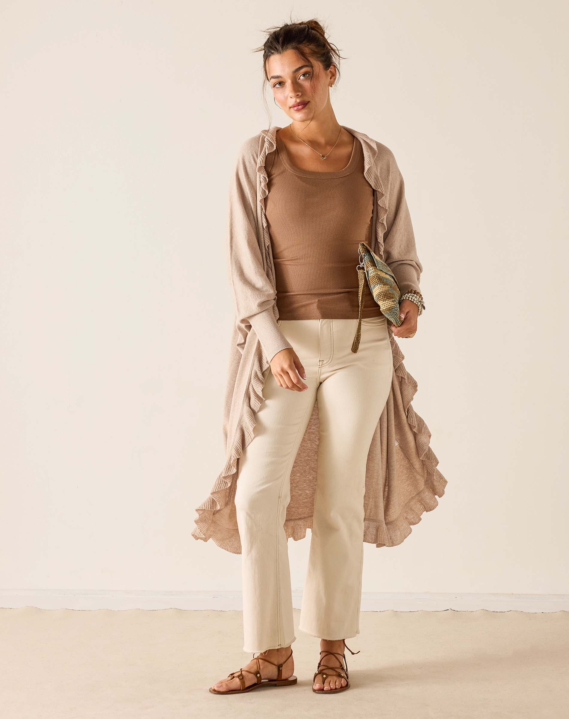 Woman wearing a beige outfit with a long duster against a white background