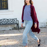 MERSEA women's travel-friendly women's travel-friendly wine-colored ruffled kimono wrap worn over a striped knit top and light denim jeans.