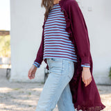 Wine-colored ruffle kimono wrap over a striped knit top and light-wash jeans.