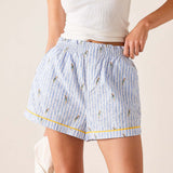 Person wearing light blue striped shorts with small patterns on a plain background