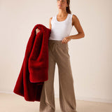 Women's travel-friendly garnet red faux fur throw draped over a woman's shoulder.