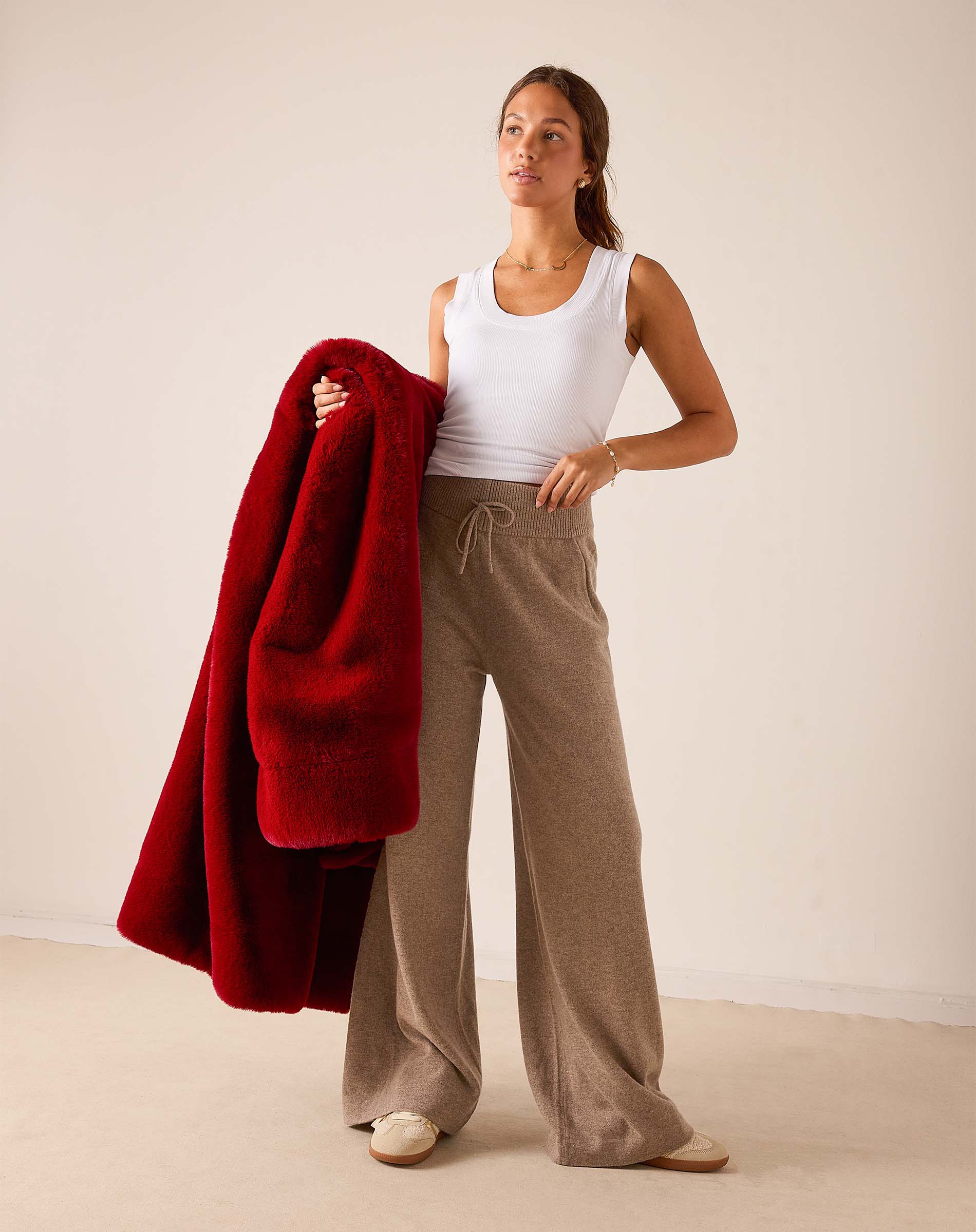 Women's travel-friendly garnet red faux fur throw draped over a woman's shoulder.