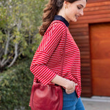 Woman holding a red handbag against a plain background