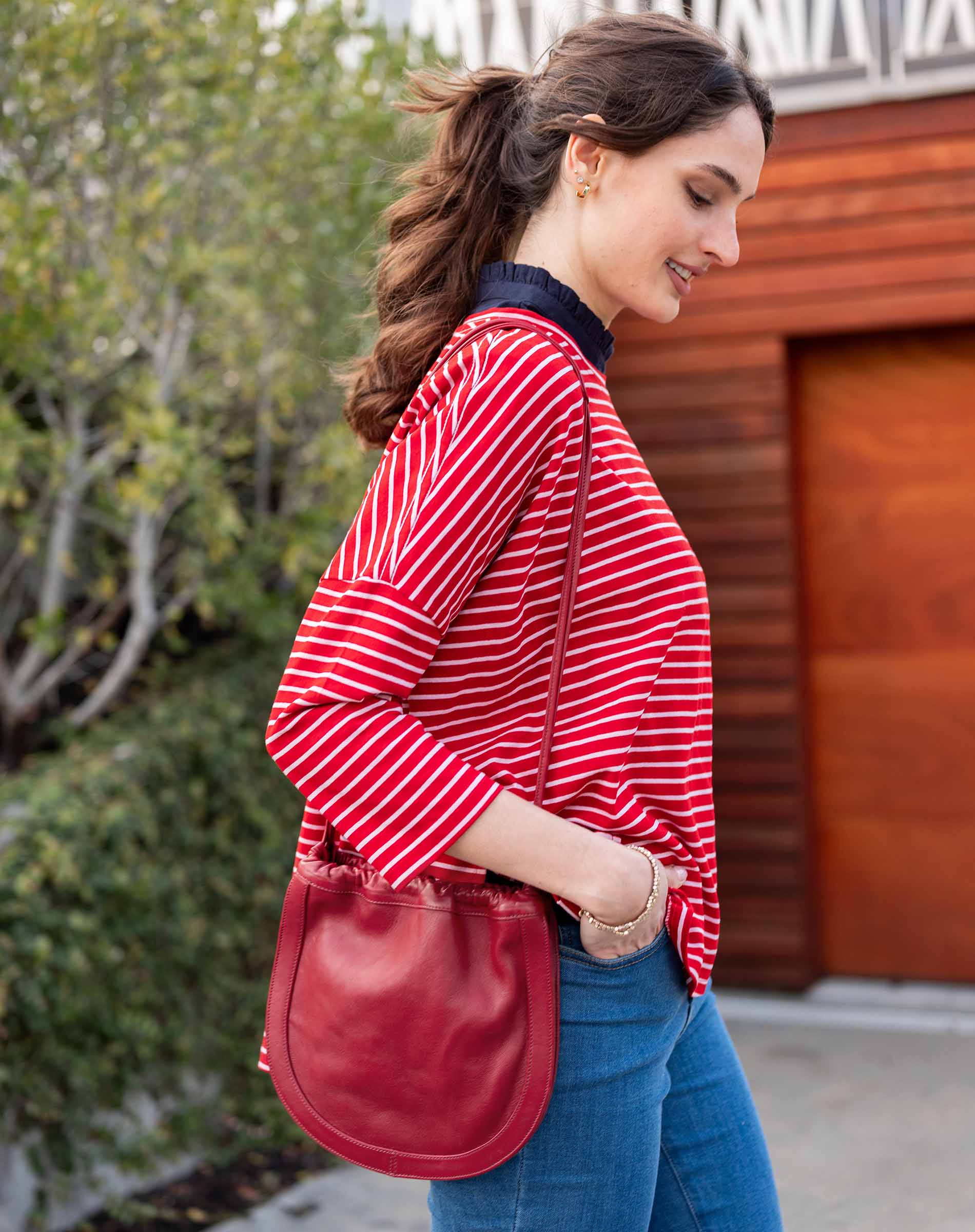 Woman holding a red handbag against a plain background