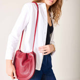 Woman holding a red handbag against a plain background
