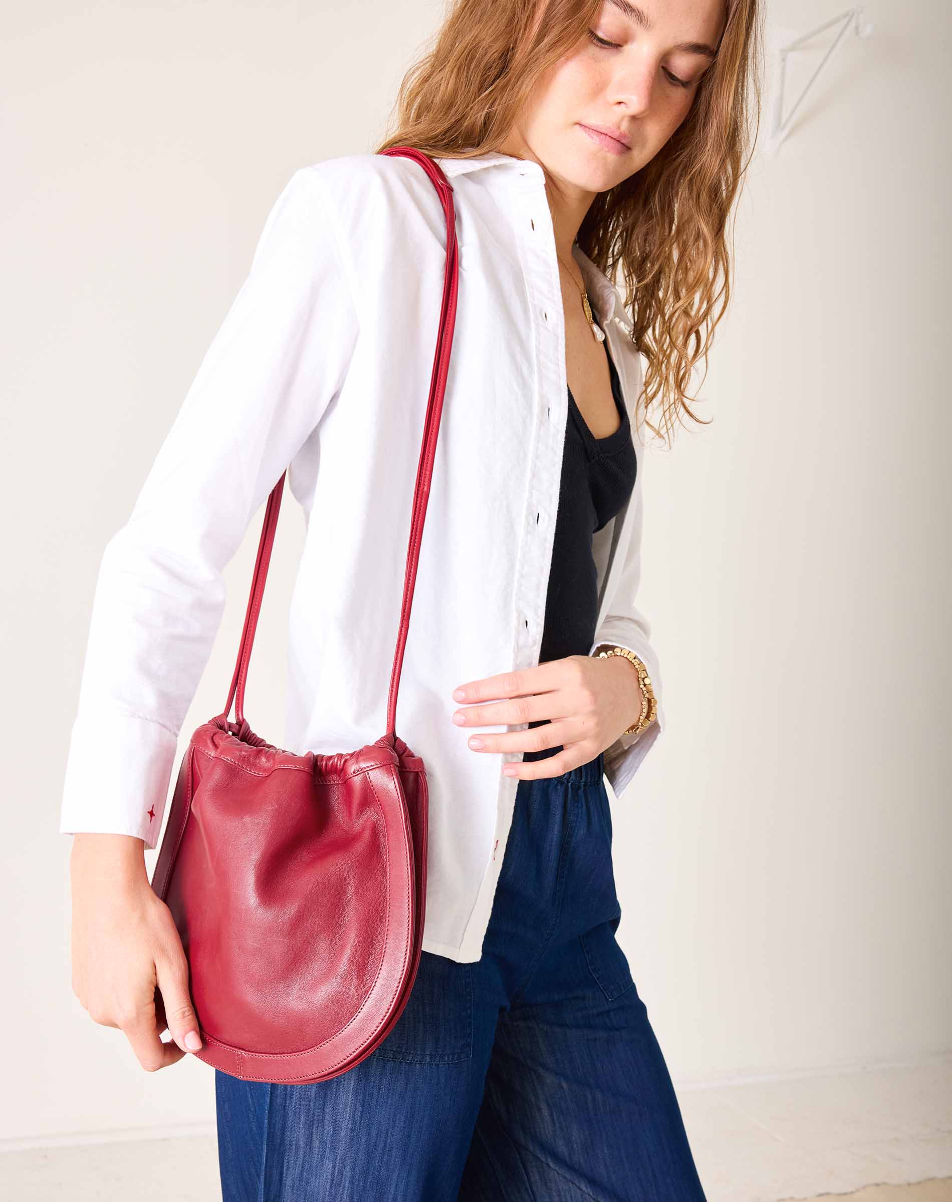 Woman holding a red handbag against a plain background