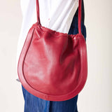 Woman holding a red handbag against a plain background