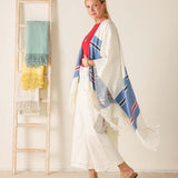 Woman wearing a colorful scarf with a ladder holding more scarves in the background.