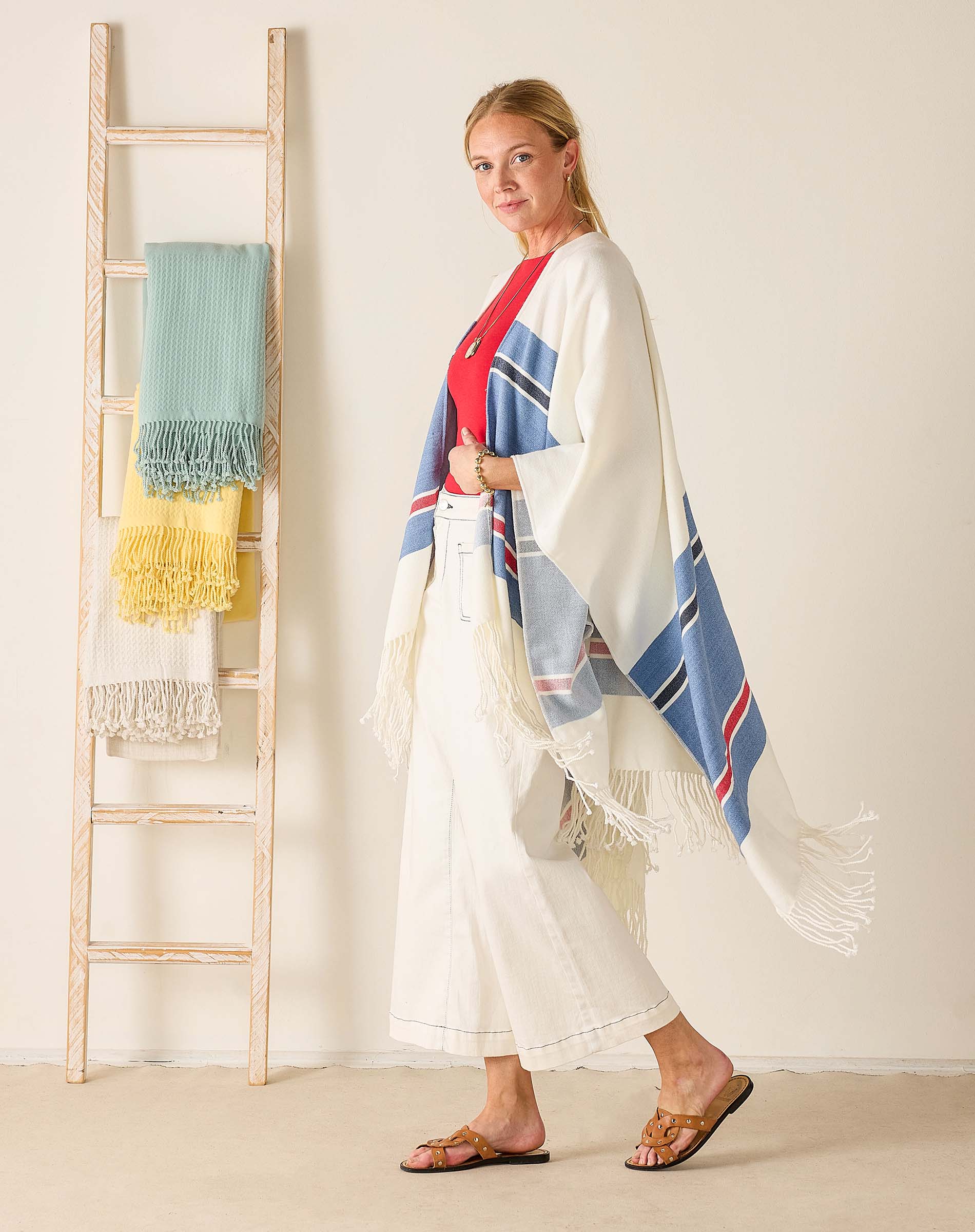 Woman wearing a colorful scarf with a ladder holding more scarves in the background.