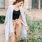 Woman standing in a garden with flowers and a building in the background