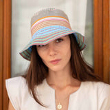 Woman wearing a colorful striped bucket hat against a neutral background