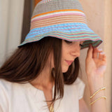 Woman wearing a colorful striped bucket hat against a neutral background