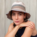 Woman wearing a striped bucket hat against a neutral background