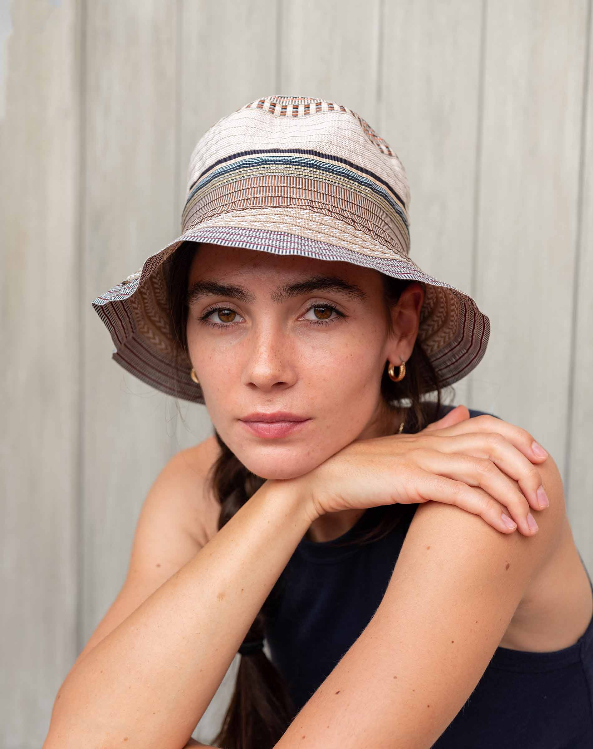 Woman wearing a striped bucket hat against a neutral background