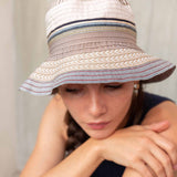 Person wearing a wide-brimmed hat with striped pattern against a neutral background