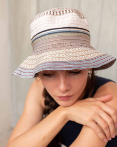 Person wearing a wide-brimmed hat with striped pattern against a neutral background