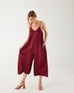woman wearing mersea coco satin jumpsuit in garnet against white backdrop