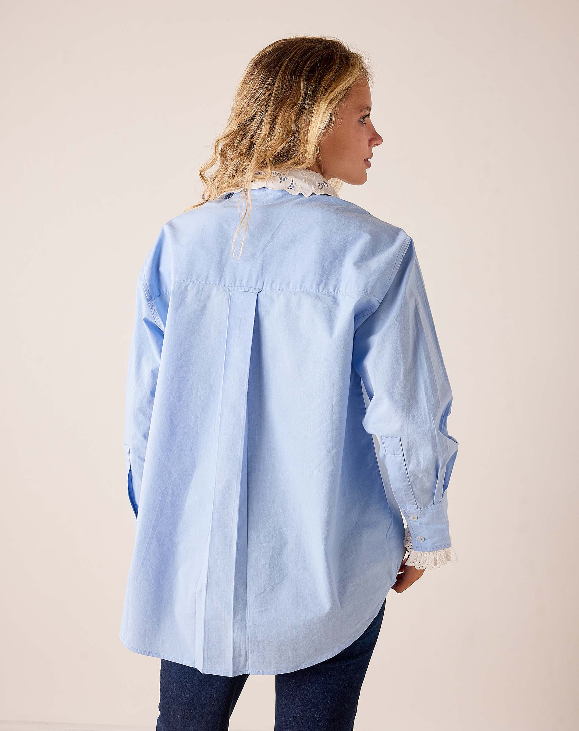Back view of women's travel-friendly light blue oversized cotton button-down shirt with a removable eyelet lace collar.