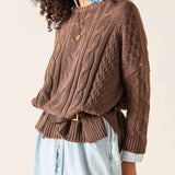 Brown cable knit oversized sweater with textured stitch patterns and ribbed cuffs.