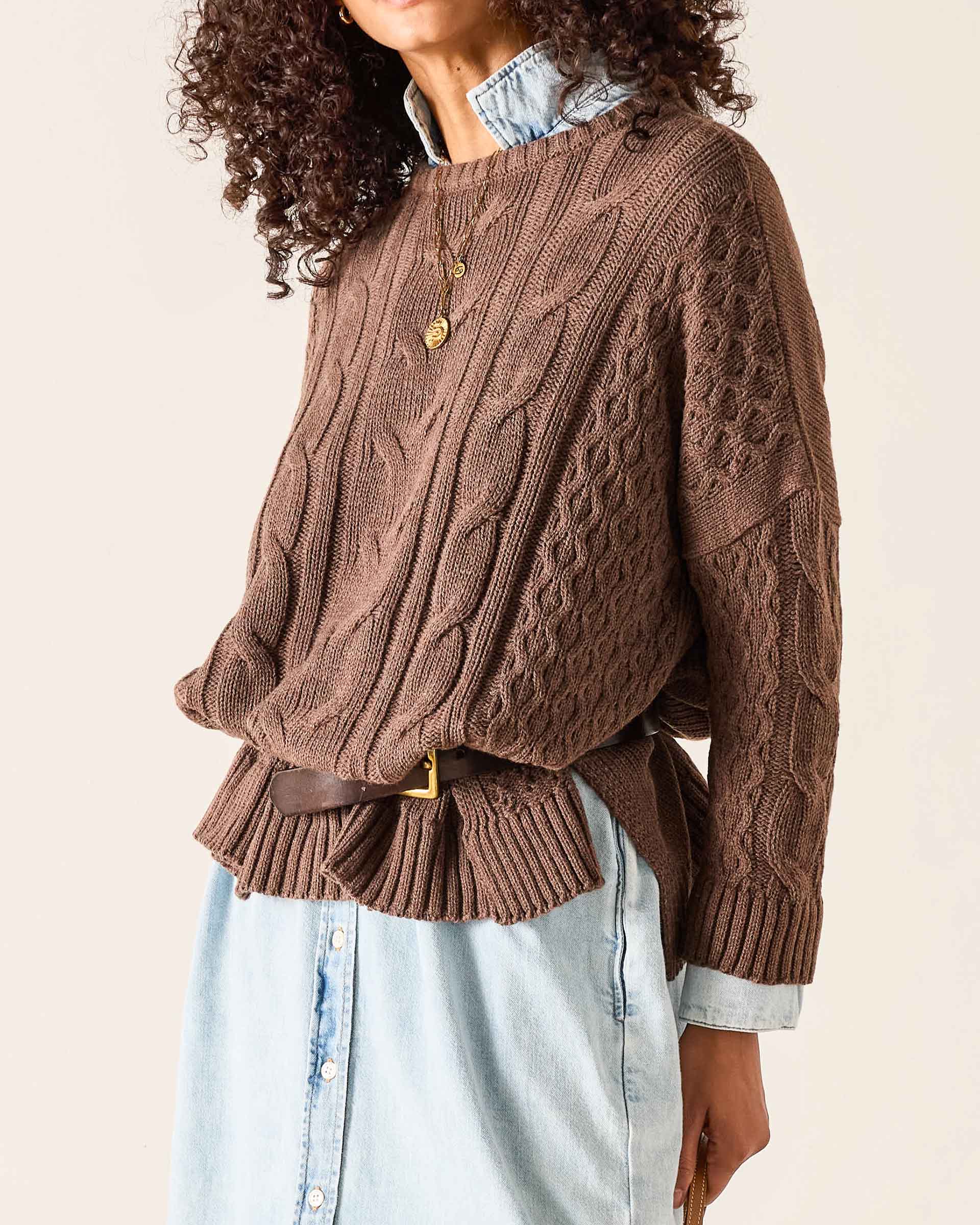 Brown cable knit oversized sweater with textured stitch patterns and ribbed cuffs.