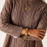 Brown cable-knit sweater featuring a chunky textured weave and decorative knit patterns.