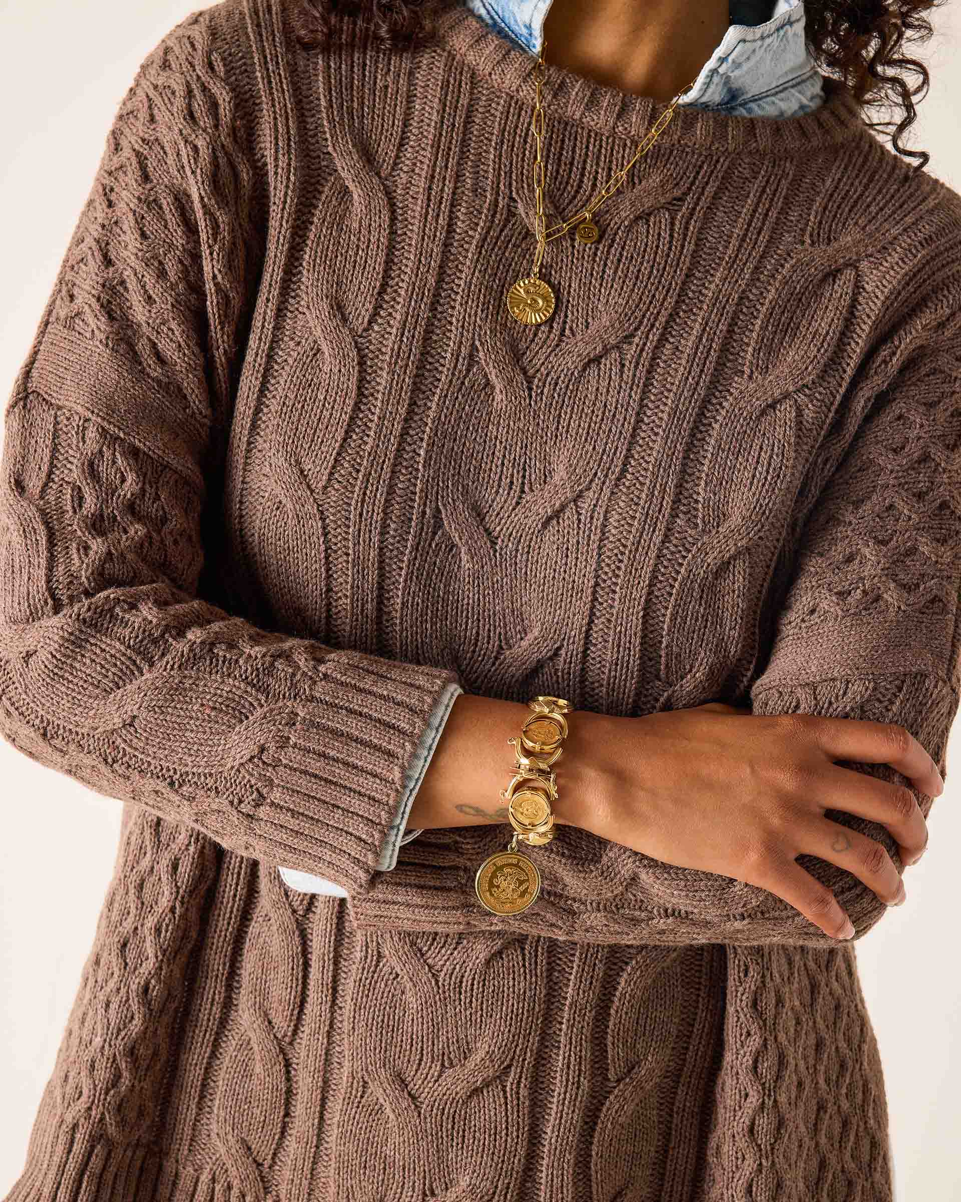 Brown cable-knit sweater featuring a chunky textured weave and decorative knit patterns.