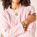 Light pink cable knit sweater with ruffled collar and textured details.