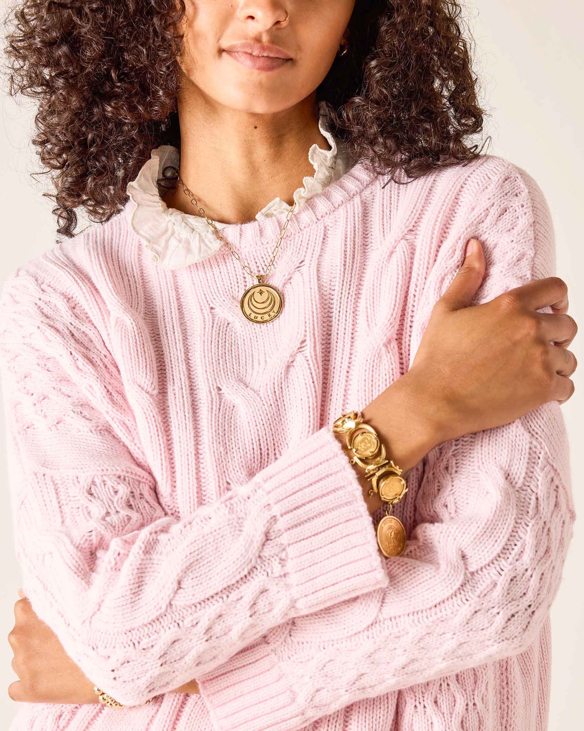 Light pink cable knit sweater with ruffled collar and textured details.