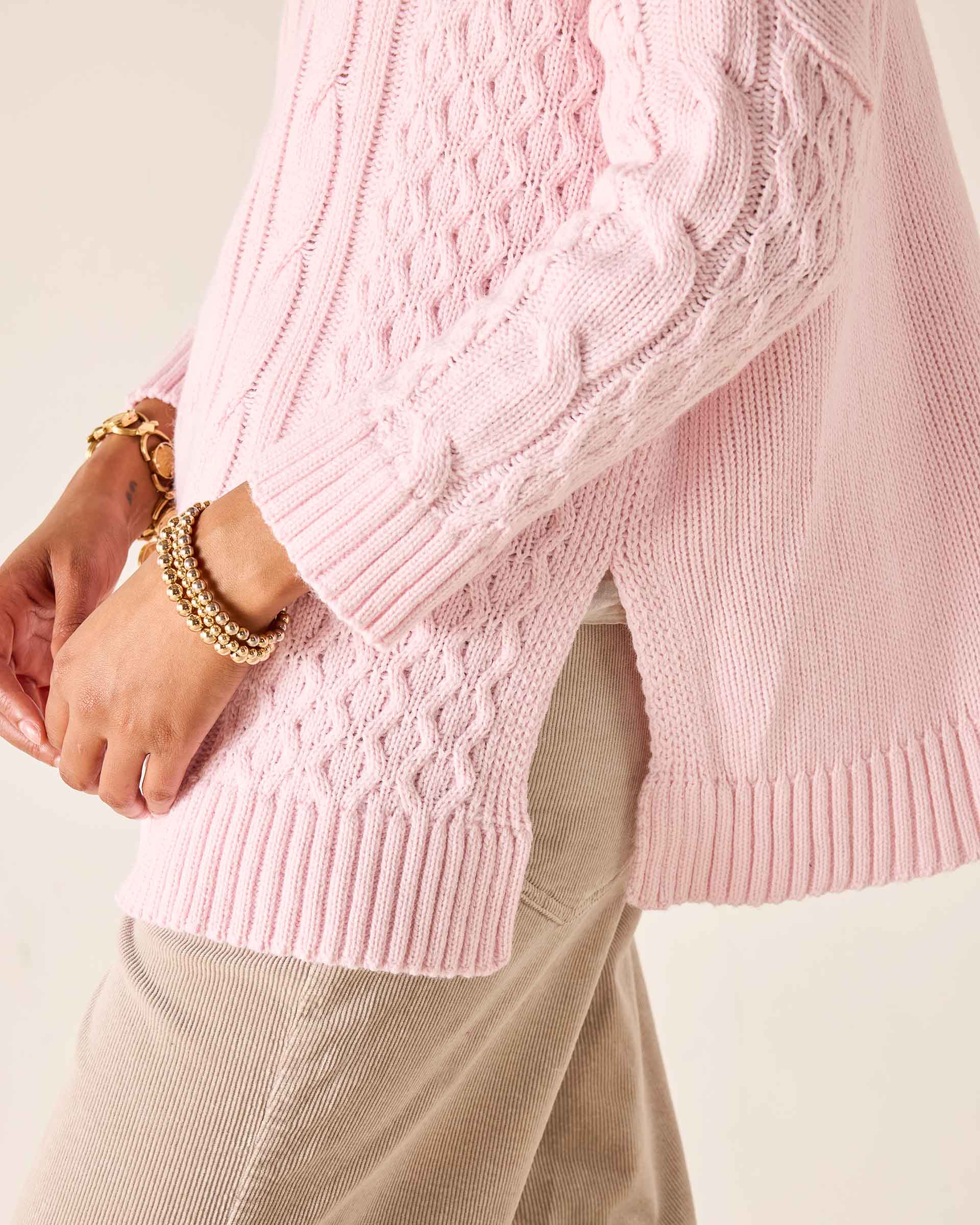 Light pink cable knit sweater with ribbed cuffs and hem.