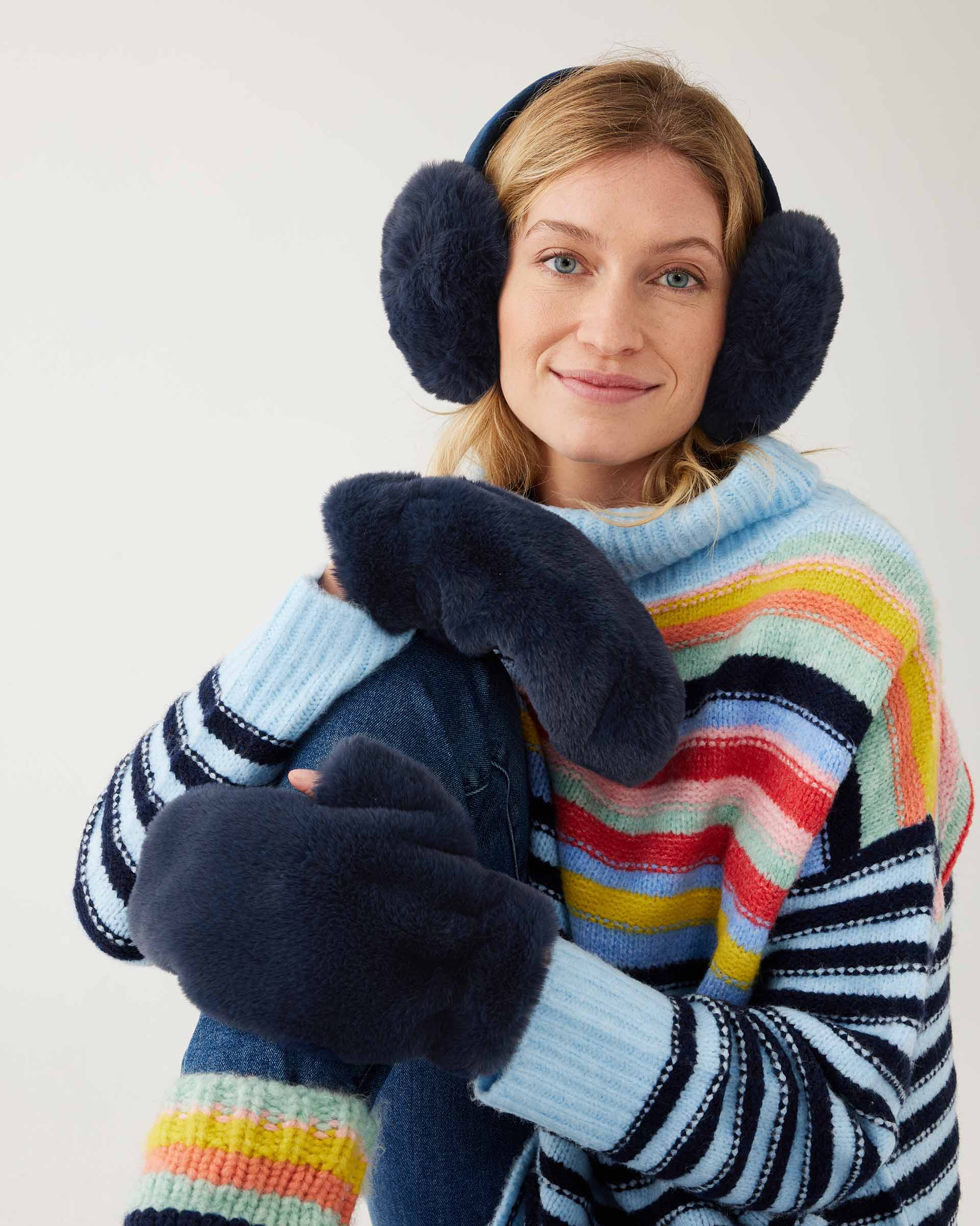 closeup of woman wearing mersea cozy cabin faux fur mittens scarf and earmuffs in oxford blue