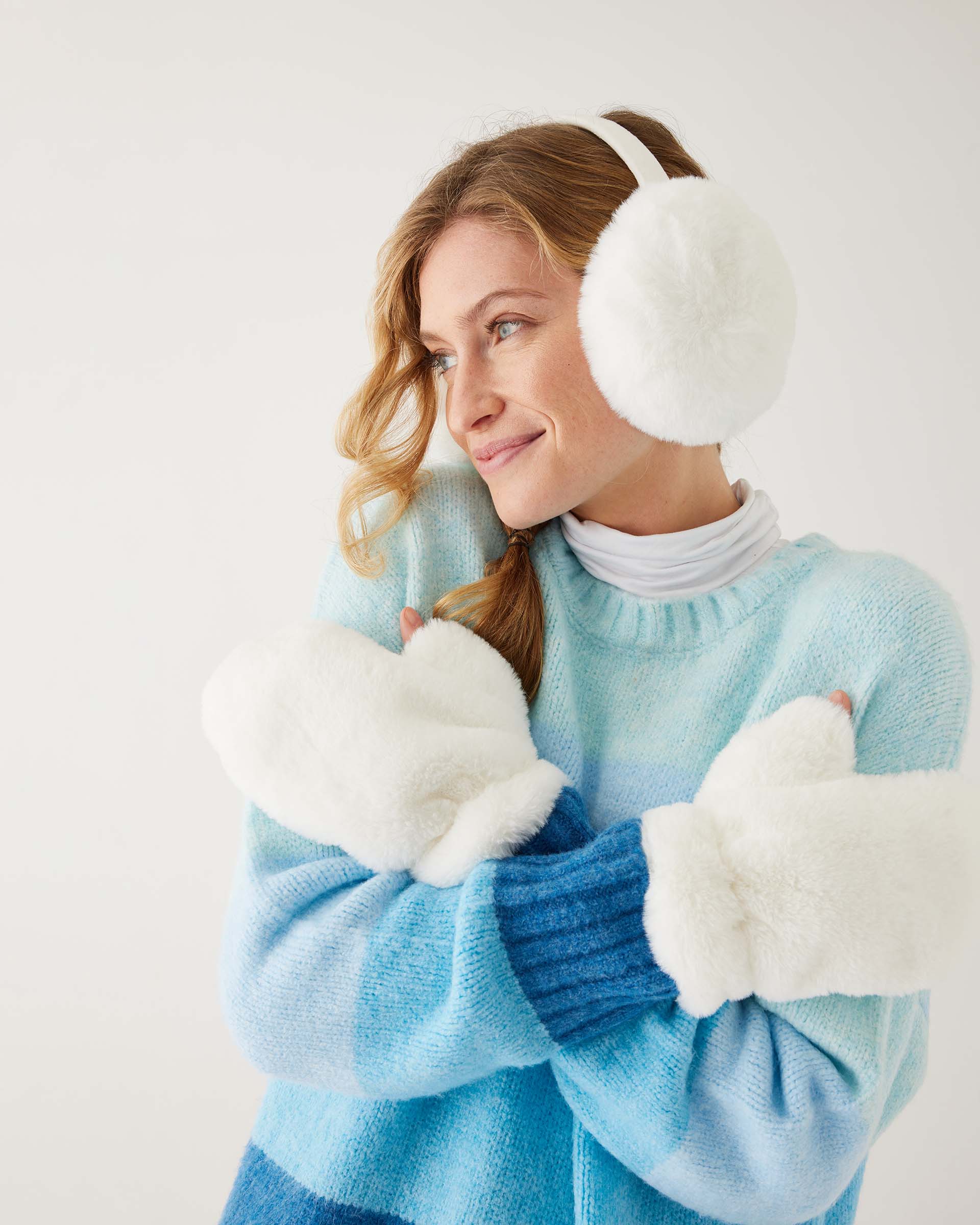 woman wearing mersea cozy cabin faux fur mittens and earmuffs in whisper white