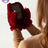 closeup of woman wearing mersea cozy cabin faux fur mittens in wine color with exposed thumbs using phone