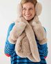 closeup of woman wearing mersea cozy cabin faux fur scarf earmuffs and mittens in oatmeal cream color